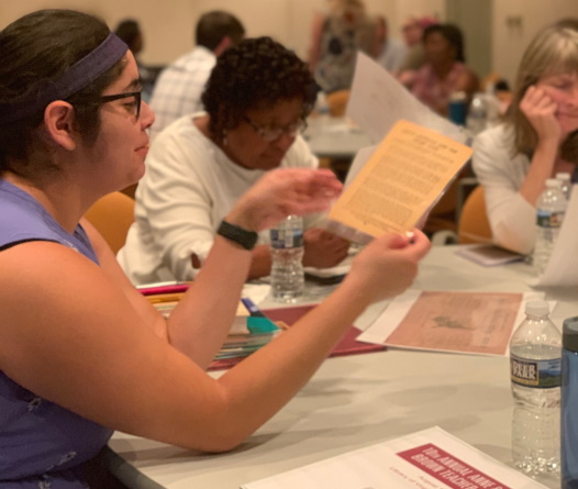 close-up photograph of a seated woman looking at a document in her hands
